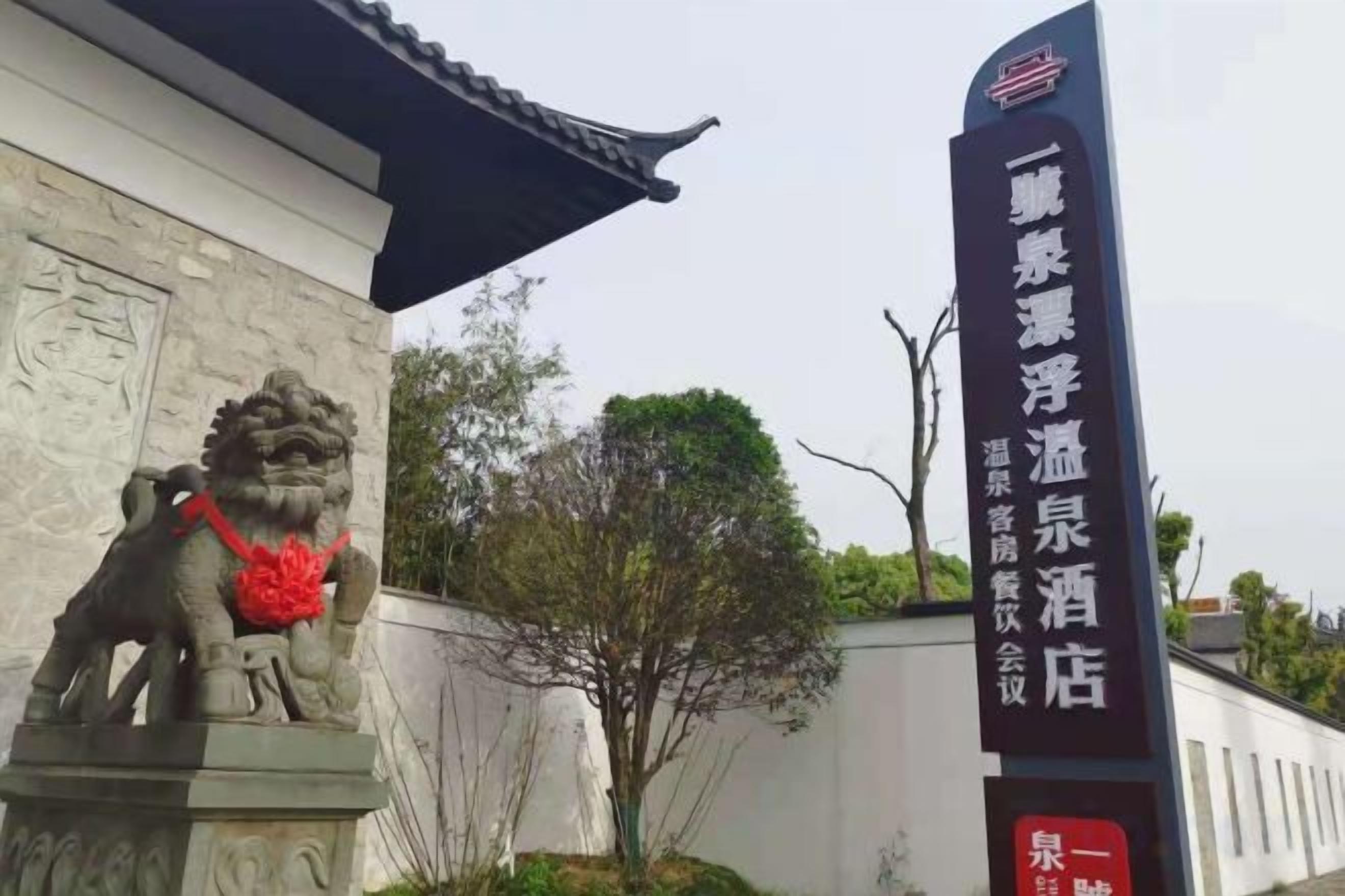 A building with a traditional Chinese architectural style, a lion statue, and a sign indicating a hotel.