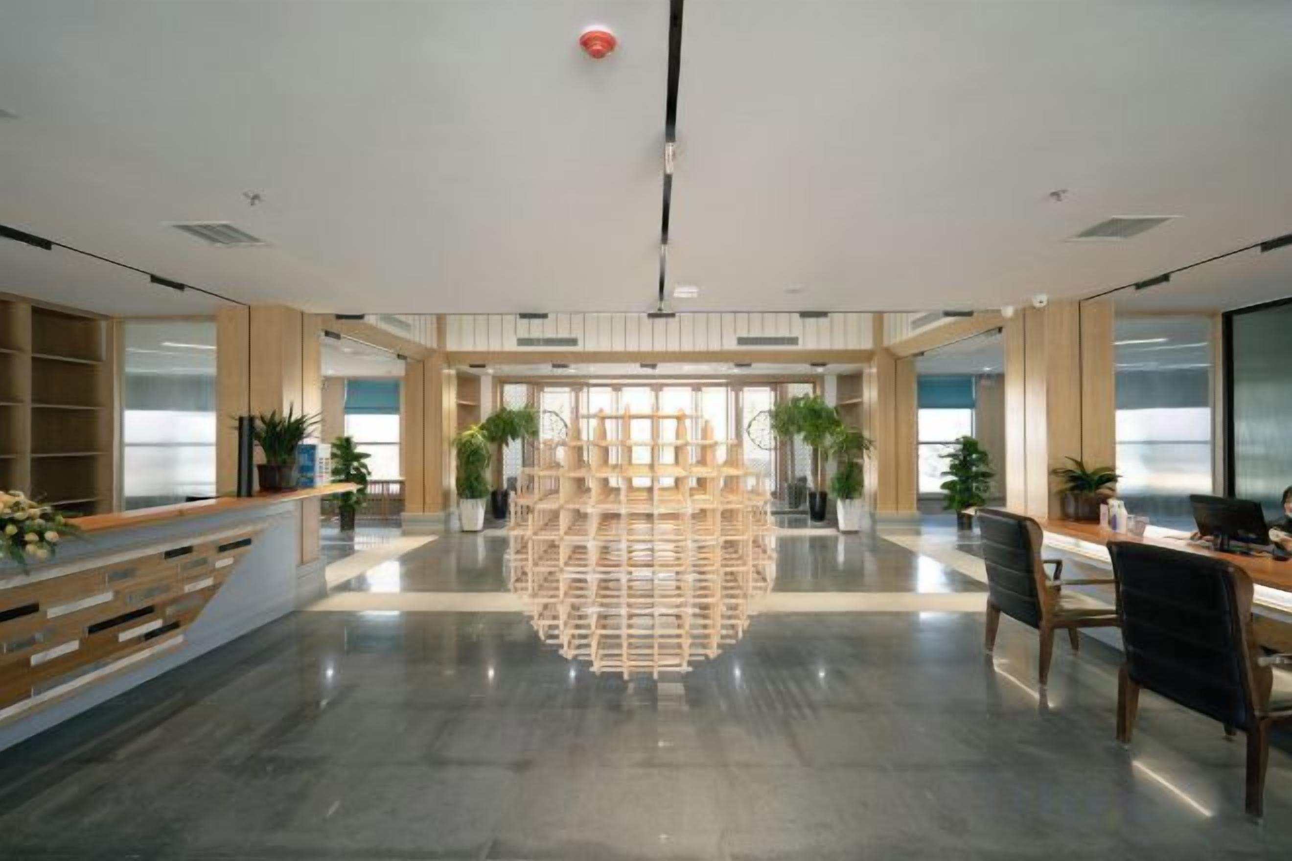 A spacious lobby with a reception desk, seating area, and potted plants.