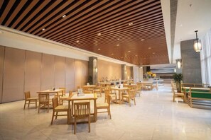 Een ruime lobby met meerdere zithoeken, een hoog plafond met houten latten en een modern design.