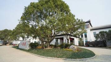 A building with a traditional architectural style, surrounded by a landscaped area with a large tree.