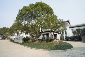 Un edificio de estilo arquitectónico tradicional, rodeado de un área ajardinada con un árbol grande.