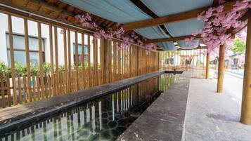A corridor with a reflective water feature, wooden columns, and a covered walkway.