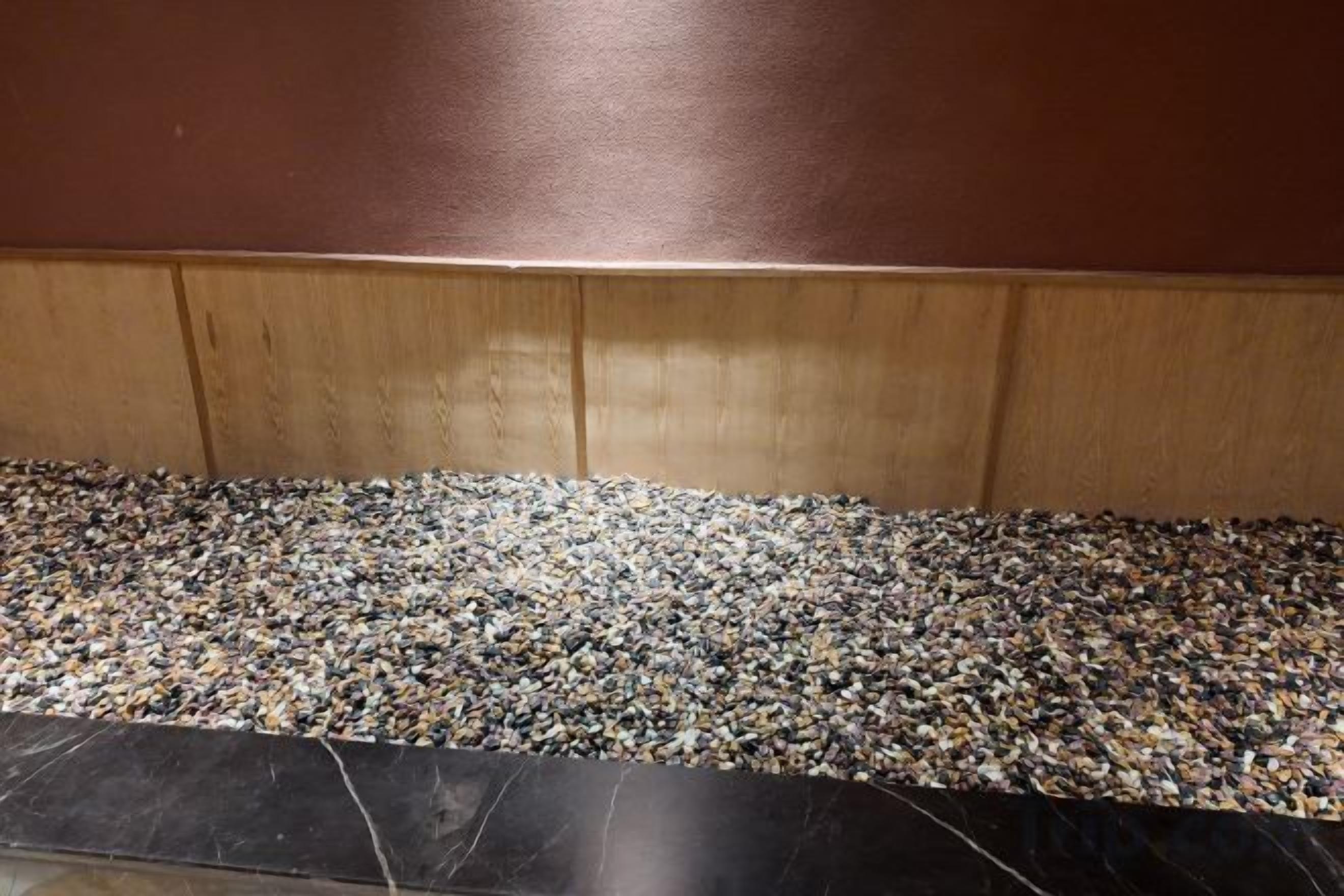 A floor with a pebble pattern and a wooden panel wall.