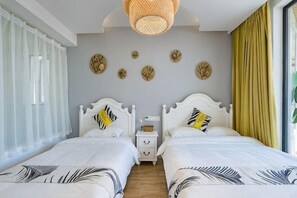 Habitación de hotel con dos camas, un ventanal grande, una lámpara de techo y adornos en la pared.
