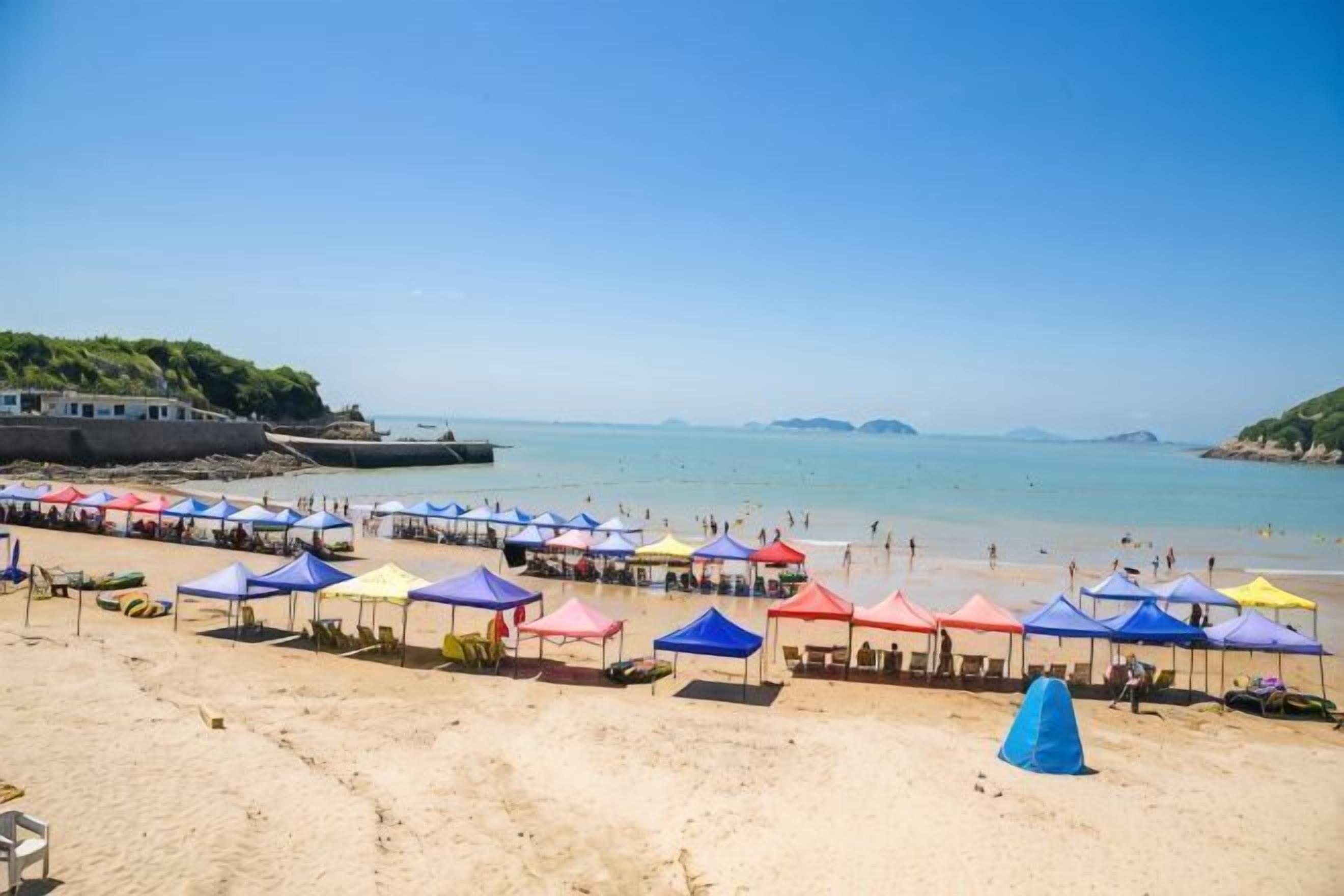 A beach with rows of colorful umbrellas and a sandy shore.