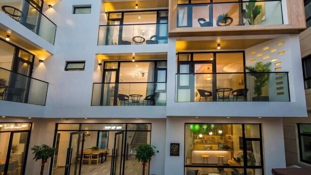A multi-story hotel with glass balconies, indoor seating areas, and a visible restaurant. - Shengsiya home stay (Shengsi)