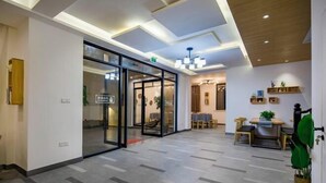 A modern hotel lobby with a glass door entrance, a reception desk, and a dining area with tables and chairs. - Shengsiya home stay (Shengsi)