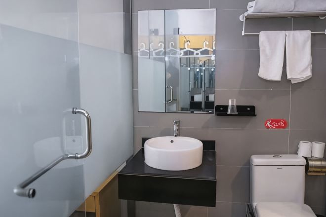 A modern bathroom with a white sink, a mirror, a towel rack, and a toilet.