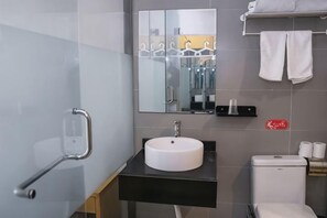 Un baño moderno con lavamanos blanco, espejo, toallero y inodoro.