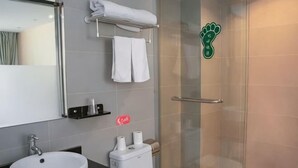 A bathroom with a glass shower enclosure, a sink, a toilet, and a towel rack.