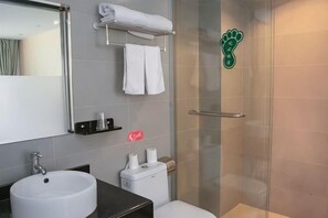 Un baño con cabina de ducha de vidrio, lavamanos, inodoro y perchero para toallas.