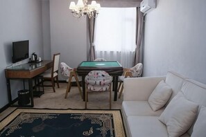 A living room with a pool table, a sofa, a TV, and a chandelier.