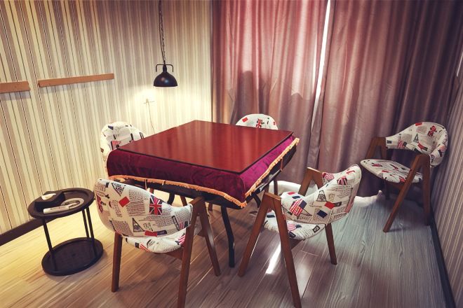 A dining area with a wooden table and chairs, a hanging lamp, and a curtain.