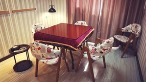 A dining area with a wooden table and chairs, a hanging lamp, and a curtain.