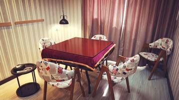 A dining area with a wooden table and chairs, a hanging lamp, and a curtain.