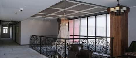 Un hall d’hôtel spacieux avec un plafond haut, un sol à motifs, un coin salon comprenant une chaise et un canapé, et un lustre décoratif.