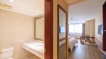 Ein Hotelzimmer mit Bad, Bett, Fernseher und Schreibtisch.