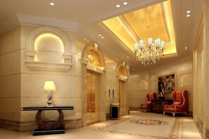 A lobby with a chandelier, a reception desk, and a seating area with red chairs. - Vienna Hotel (Songbin Road Metro Station, Baoshan) (Shanghai)