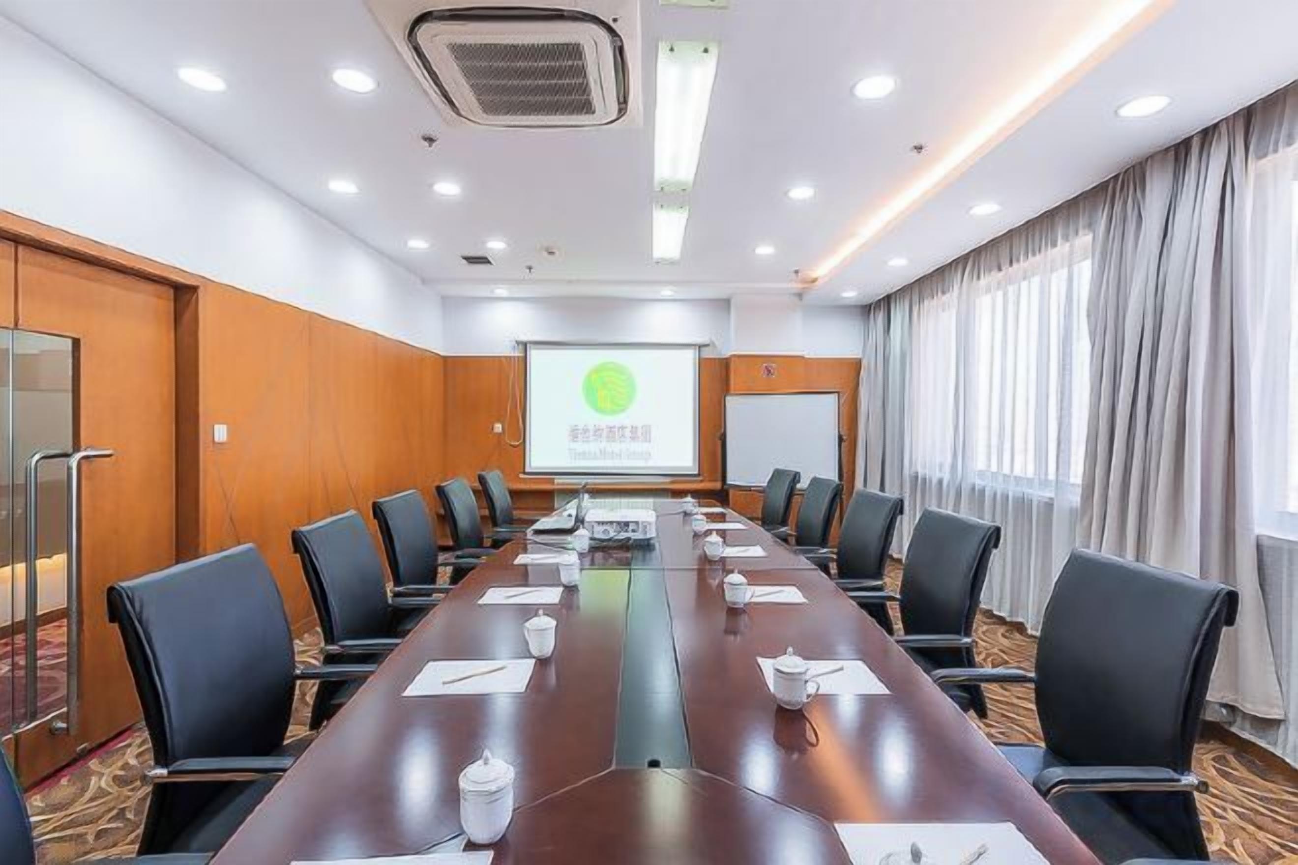 A conference room with a long table, chairs, a projector screen, and a presentation.
