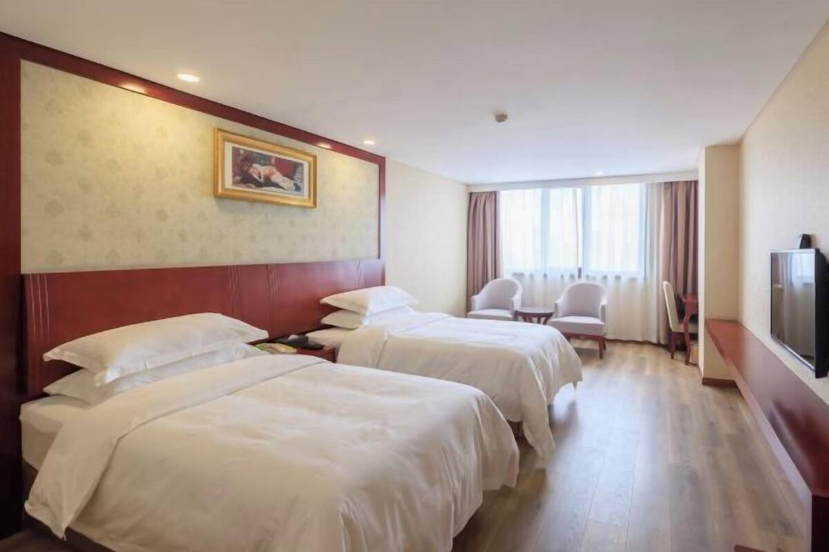 Une chambre d’hôtel avec deux lits, une télévision, un bureau et une chaise.