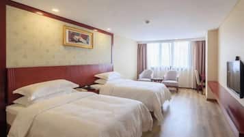 A hotel room with two beds, a television, a desk, and a chair.