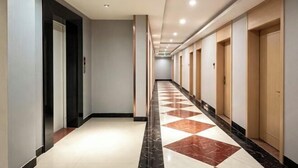 A hotel corridor with a checkered floor pattern, doors on both sides, and a ceiling with recessed lighting. - Jingyuan Boutique Hotel (Wuxuan)