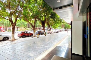 Una acera con árboles, coches aparcados e hidrante.