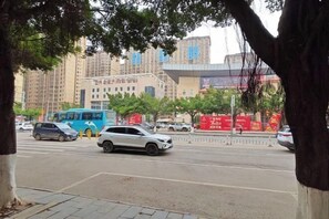 A busy urban street with a blue bus, a white car, and tall residential buildings in the background.