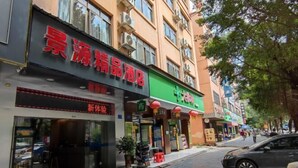 A street view with a hotel named "Accurate" on the left, featuring a modern facade and large windows. - Jingyuan Boutique Hotel (Wuxuan)