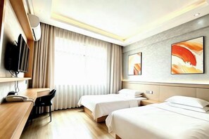 Habitación de hotel con dos camas, un escritorio, una silla, televisión y obras de arte en las paredes.