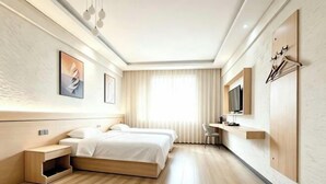 A modern hotel room with a large bed, bedside tables, a TV, and a window with curtains. - Jingyuan Boutique Hotel (Wuxuan)
