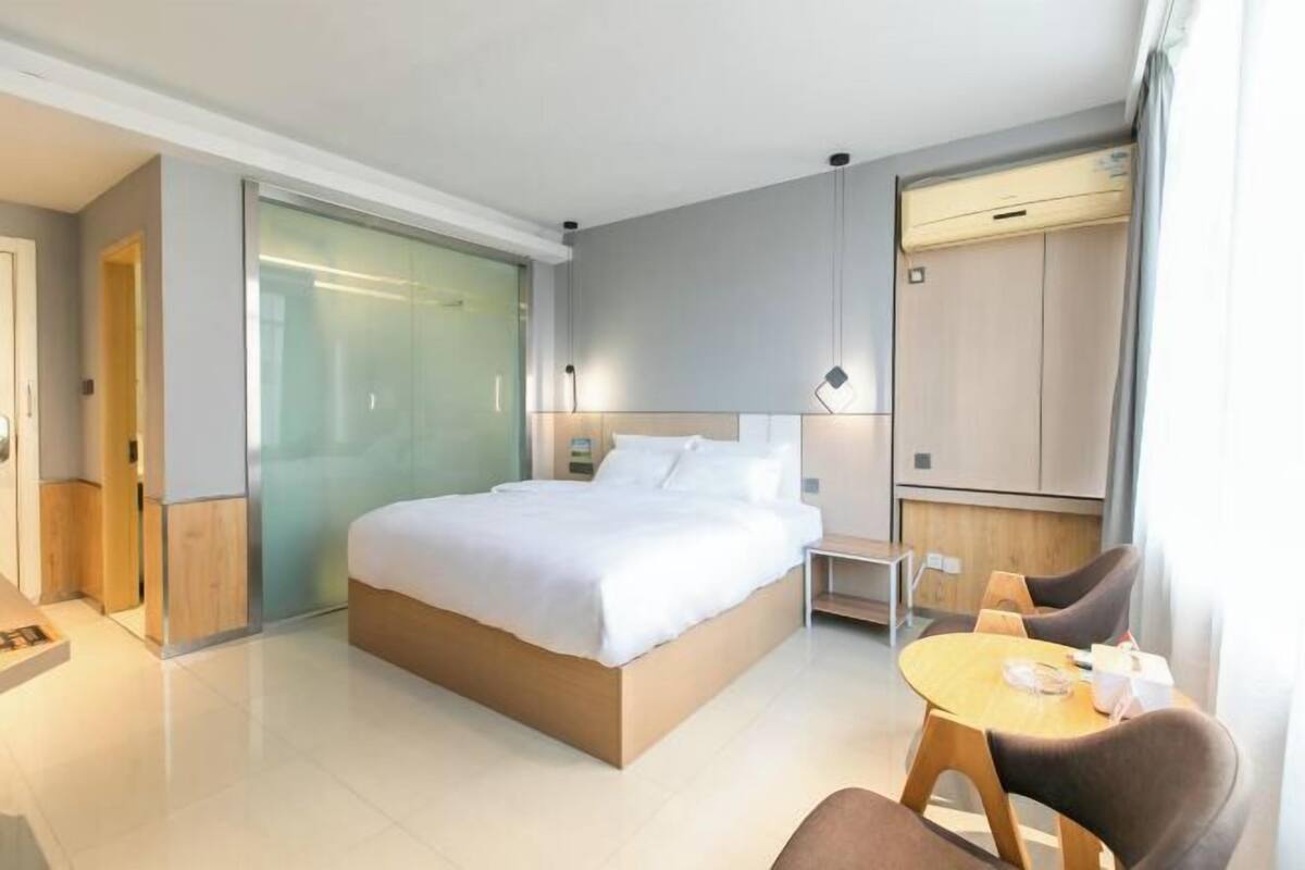 Habitació d'hotel moderna amb un llit gran, una taula petita i una cadira.