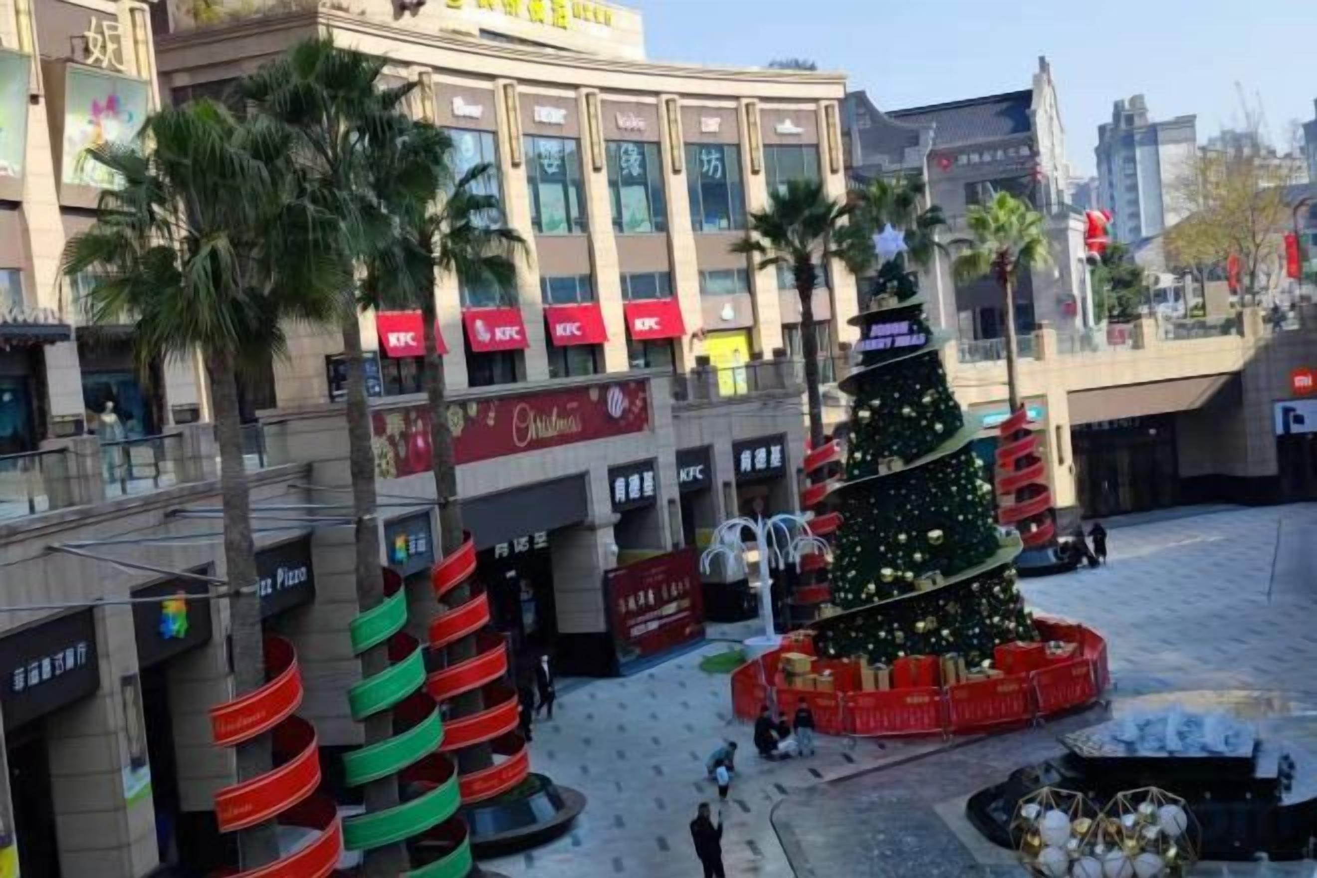 Un centre commercial avec un grand sapin de Noël et un restaurant KFC.