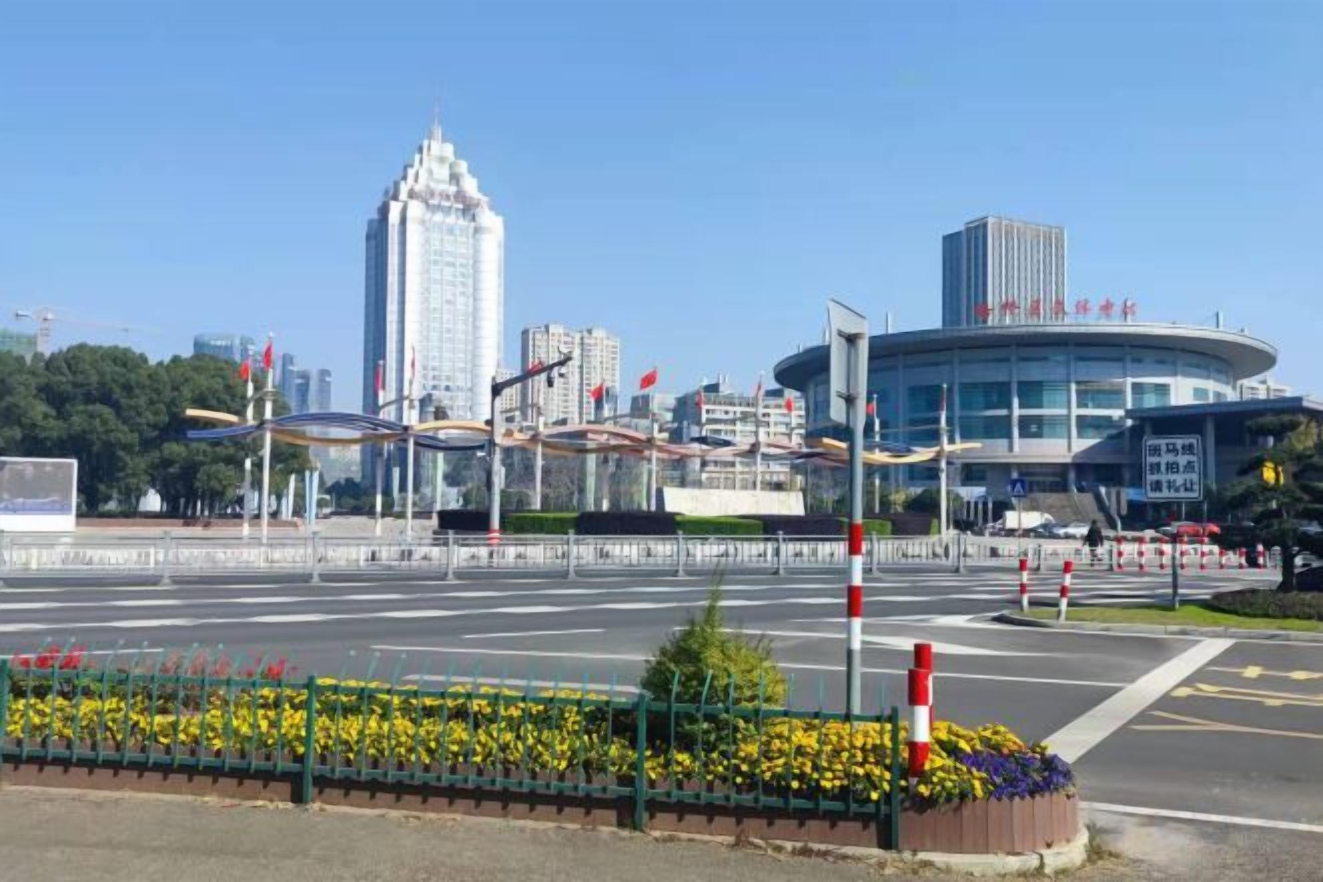 Um edifício moderno com fachada curva, rodeado por área ajardinada com flores.