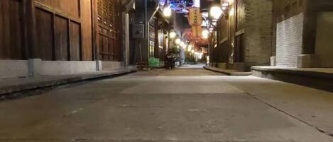 Una calle estrecha flanqueada por edificios, iluminada por luces colgantes.