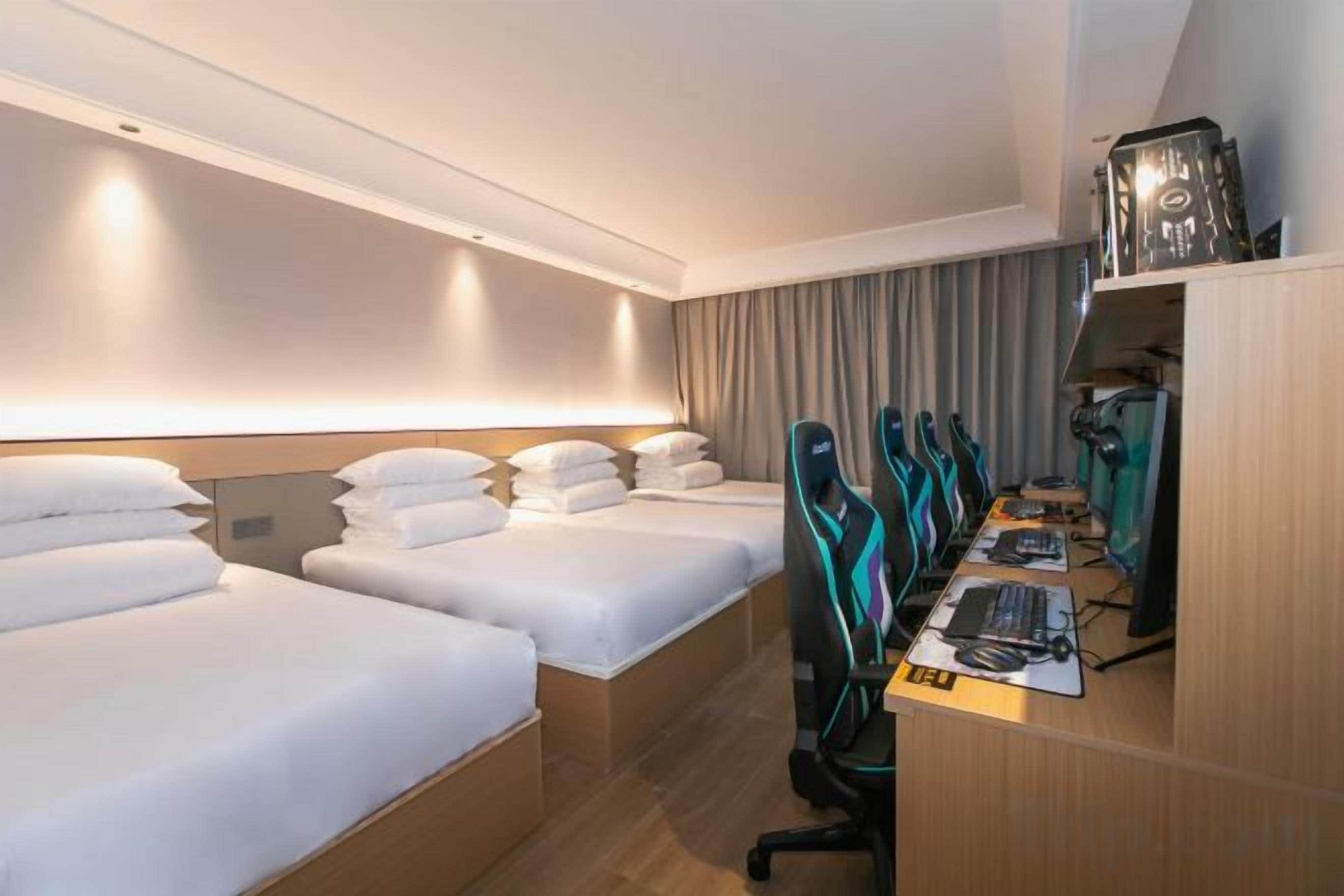 A hotel room with two beds, a desk with a computer, and a chair.