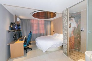A modern hotel room with a round bed, a desk with computers, a shower area, and a large window with curtains. - 123 Hotel (Taizhou)