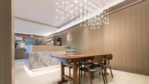 Eine moderne Hotelhalle mit einem Holzbüro, einer Marmor-Theke und einem Kronleuchter.