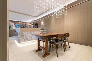 Un moderno vestíbulo de hotel con un mostrador de recepción de madera, una encimera de mármol y una lámpara de araña.