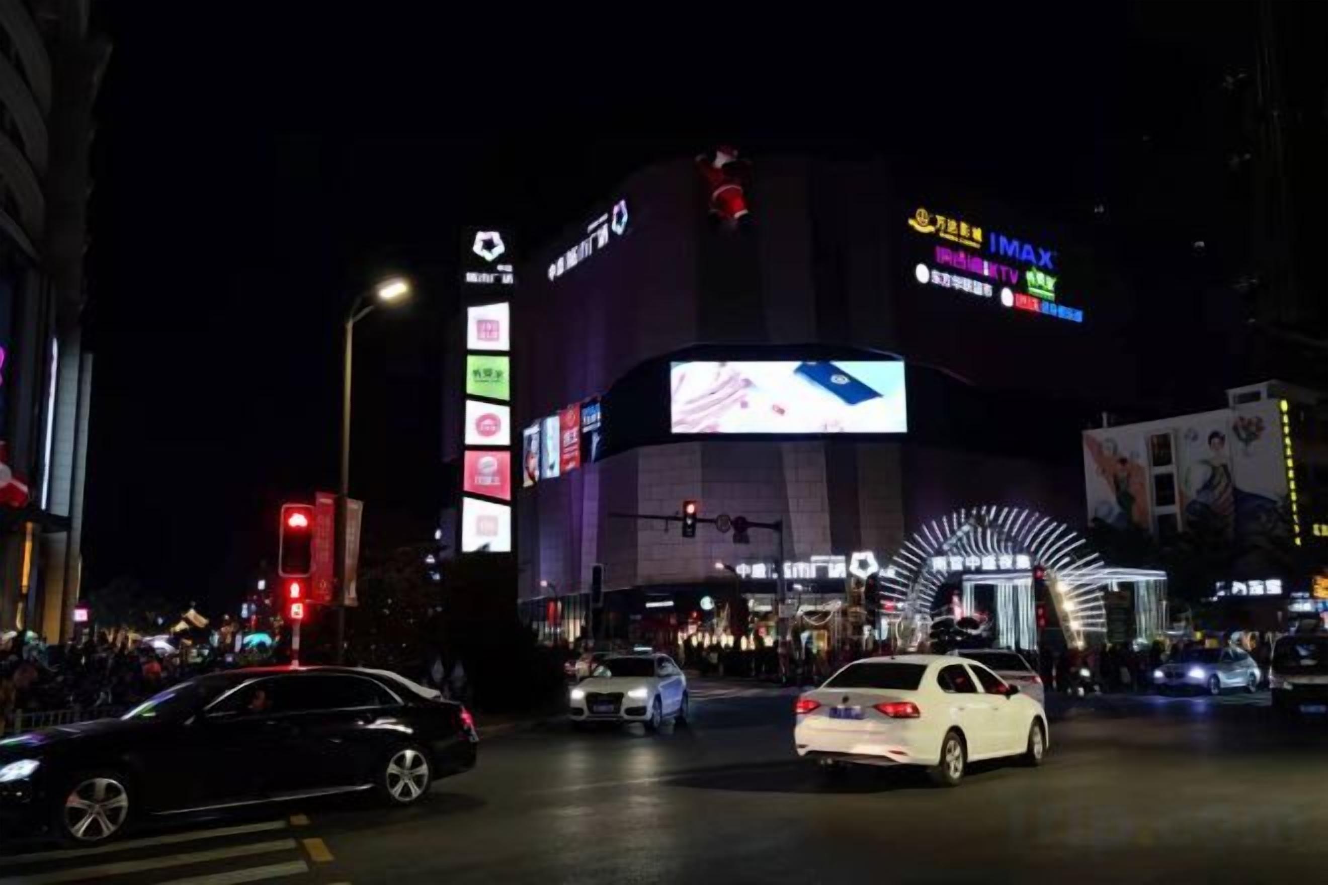 Una calle urbana concurrida de noche, con un edificio destacado que presenta señalización iluminada y un amplio acceso en arco.