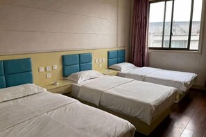 A hotel room with three beds, a wooden headboard, a window with a view, and a curtain. - Luoshen Hostel (Shanghai)