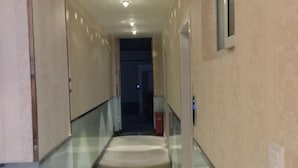 A corridor with a glass railing, beige walls, and a door at the end. - Bai Ying Hostel (Shanghai)