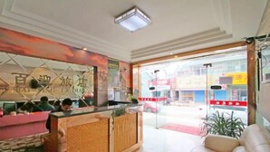 A hotel reception area with a glass partition, a reception desk, and a seating area. - Bai Ying Hostel (Shanghai)