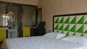 A hotel room with a bed, a mirror, a desk, and a green and white geometric headboard. - Bai Ying Hostel (Shanghai)