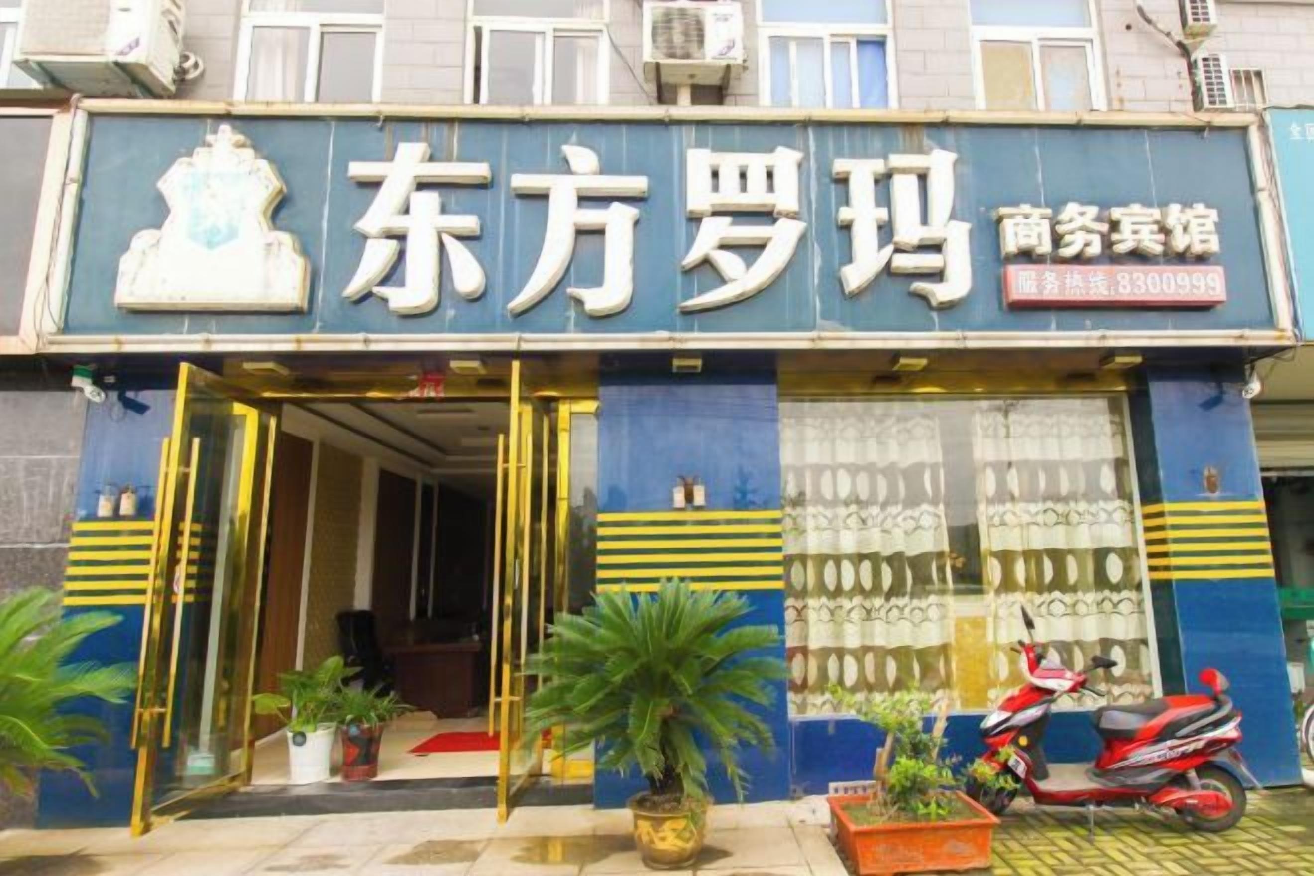 Fachada de loja com um letreiro que diz '东方罗玛 商务宾馆' e um número de contato '3300998'.