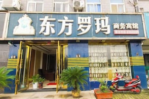 Un escaparate con un letrero que dice '东方罗玛 商务宾馆' y un número de contacto '3300998'.