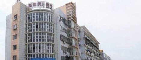 A multi-story building with a curved facade, signage for a business, and a parking lot with cars.