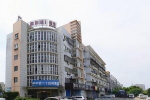 A multi-story building with a curved facade, signage for a business, and a parking lot with cars. - DONG FANG LUO MA (Wuhu)