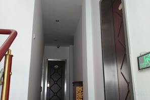 A hallway with a staircase on the left, a door at the end, and a wall-mounted sign on the right. - DONG FANG LUO MA (Wuhu)