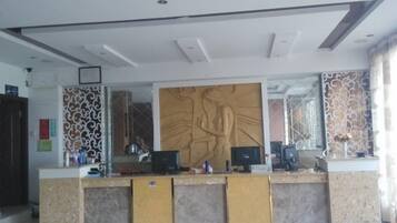 A reception desk with a large wall mural, a computer, and a telephone.
